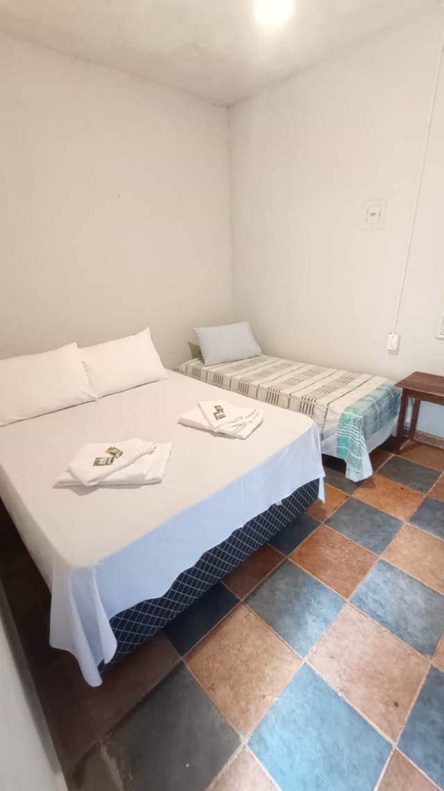 Quarto triplo da pousada com camas cobertas por colchas coloridas
