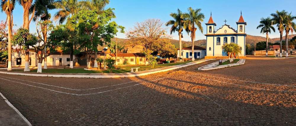 Rua de pedra com casario colonial, janelas coloridas e igreja ao fundo